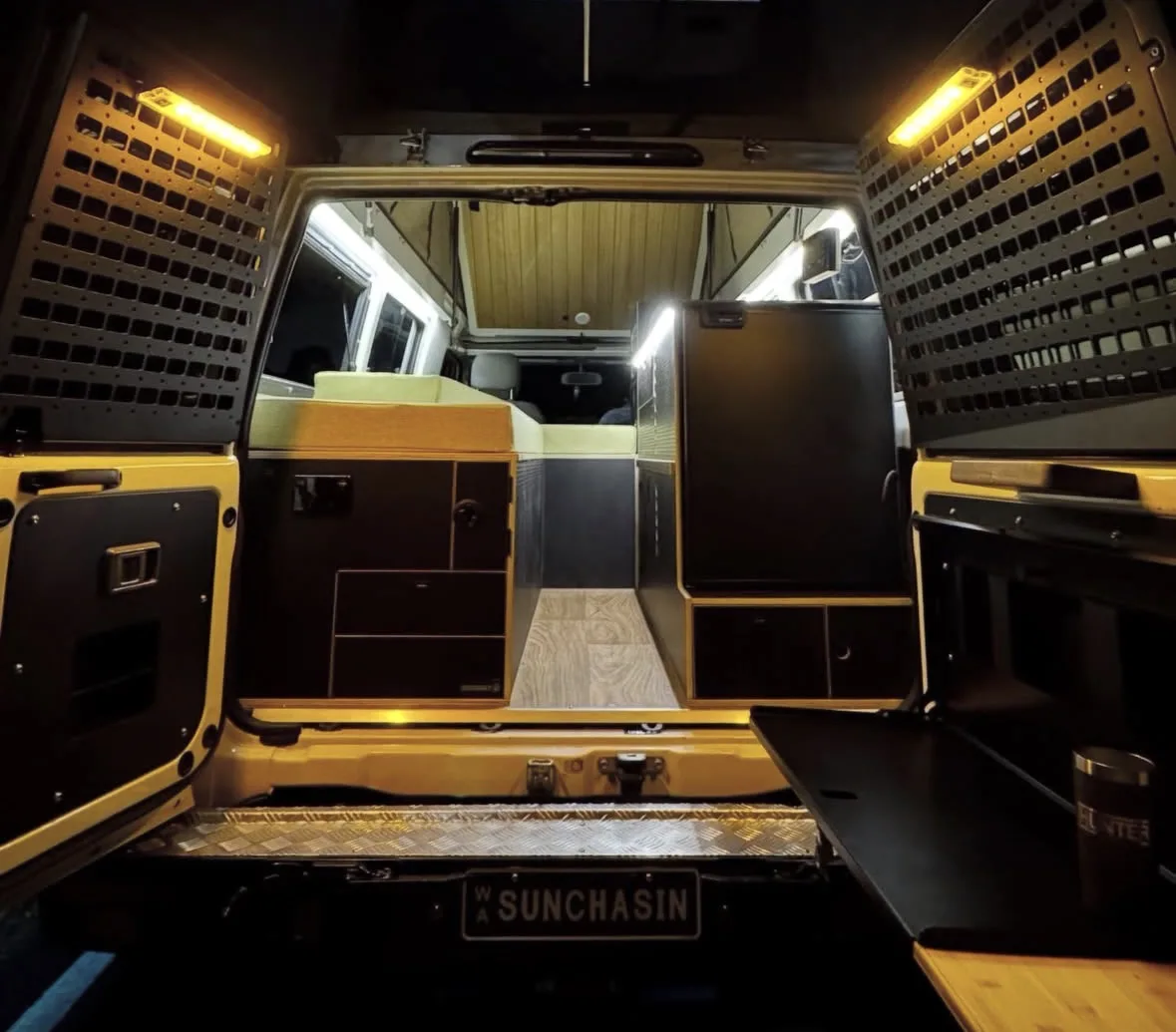 Interior view of a custom Toyota Land Cruiser Troop Carrier fit-out with storage, a bed platform, and lighting.