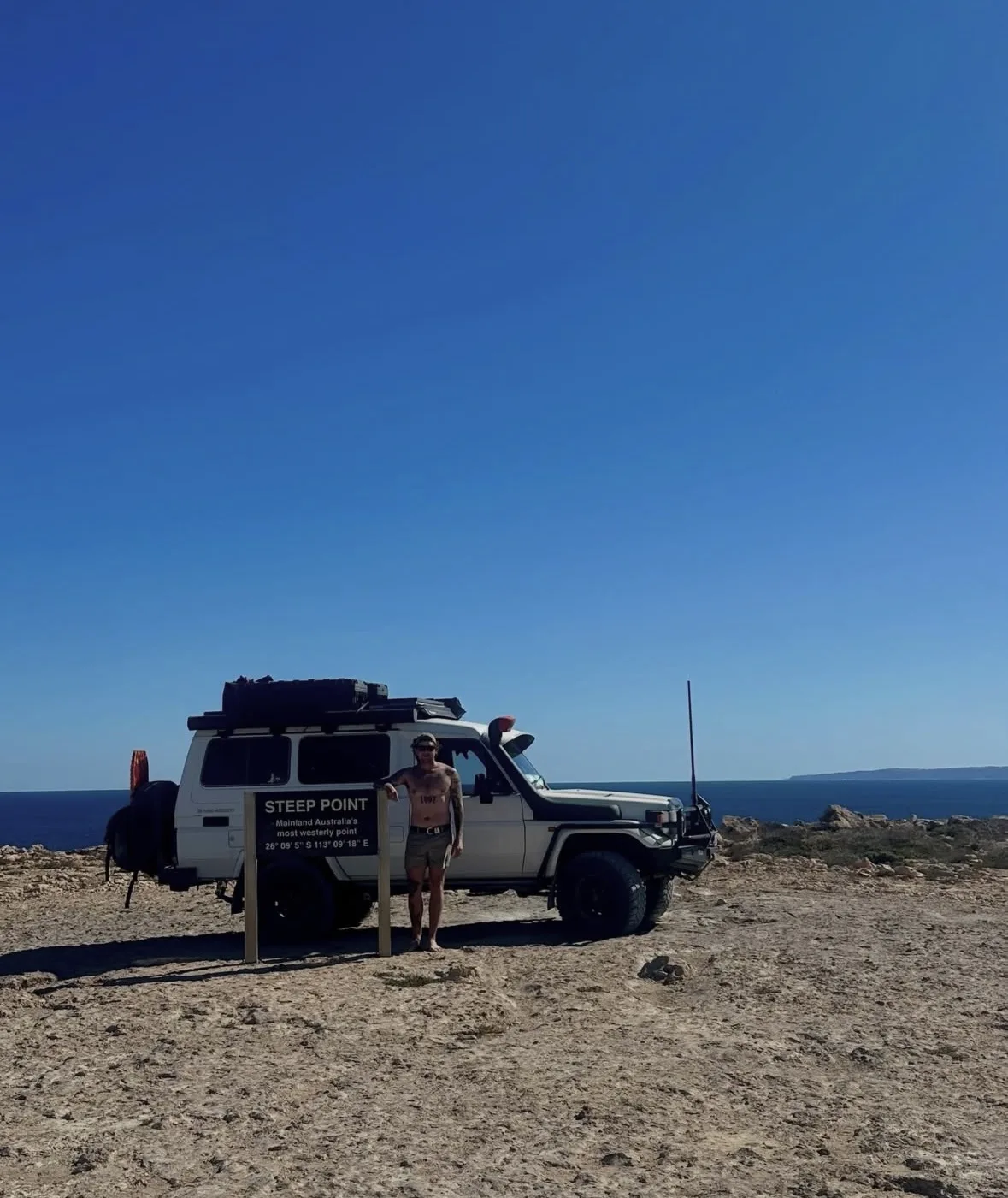 Man stands by a Toyota Land Cruiser Troop Carrier at Steep Point, mainland Australia's most westerly point.
